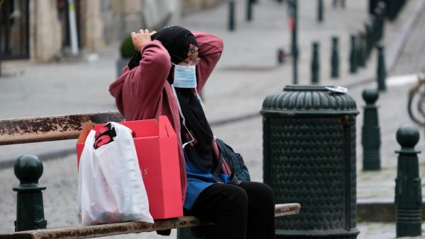 Woman on a bench adjusts her mask