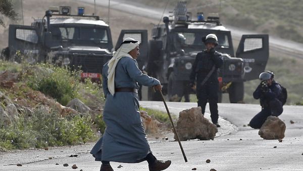 An elderly Palestinian man walks amidst clashes between demonstrators and Israeli security forces in the village of Beita, south of Nablus, after Israeli settlers announced that they would visit a historic site in the village 