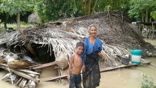 An elderly villager and her grandson stand in floodwaters in front of their damaged home in the village of Haitimuk in East Flores on April 4, 2021, after flash floods and landslides swept eastern Indonesia and neighbouring East Timor. Joy Christian / AFP An elderly villager and her grandson in floodwaters