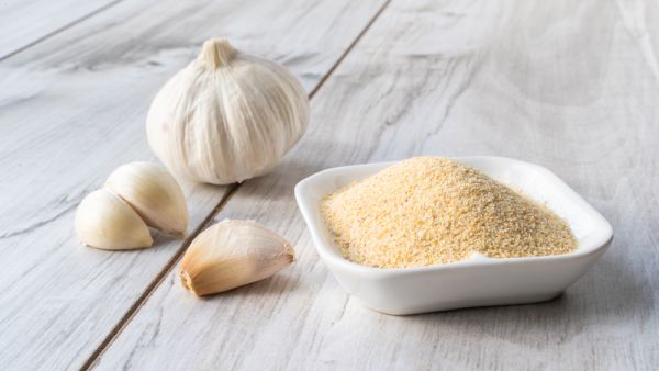 Bowl with granulated dried garlic on wooden table