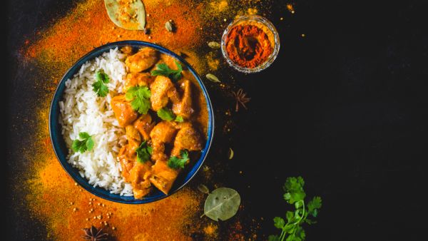 Utter chicken with basmati rice in bowl, spices, black background