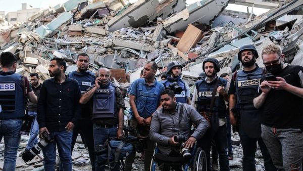 يقفون على حطام مكاتبهم , بعدما قصفت طائرات الاحتلال البرج الذي يتواجد فيه مكاتب الصحافة المحلية والدولية .