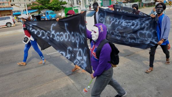 Protesters hold banners during a demonstration against the military coup in Yangon's Insein township on May 1, 2021. STR / AFP Myanmar's UN envoy pleads to the US to take action against Myanmar junta