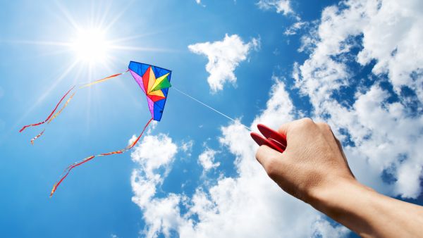 Kite flying in a beautiful sky with sun and clouds