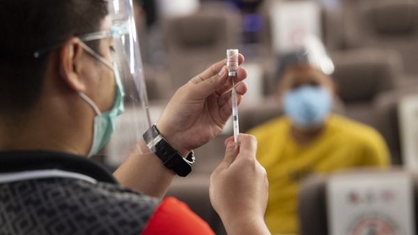 A health worker (L) prepares a vial of Chinese Sinovac vaccine against Covid-19 coronavirus inside a movie theatre turned into a vaccination centre in Taguig City suburban Manila on June 14, 2021. Ted ALJIBE / AFP Philippine President Duterte threatened to jail anyone who refuses to be vaccinated