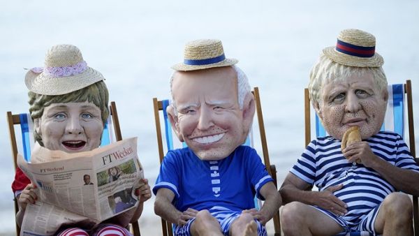 Climate activists wearing giant heads depicting the leaders of the G-7