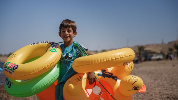 unidentified child walks along the beach to sell swimming rings