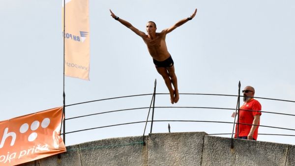A Bosnian highdiver hurls himself from the 24-metre (79-ft) high Ottoman-era Old Bridge (aka "Stari Most") in the Bosnian town of Mostar during the traditional high diving competition, on July 25, 2021. The "Old Bridge" of Mostar, listed as UNESCO herritage site, dominates the riverside scenery.