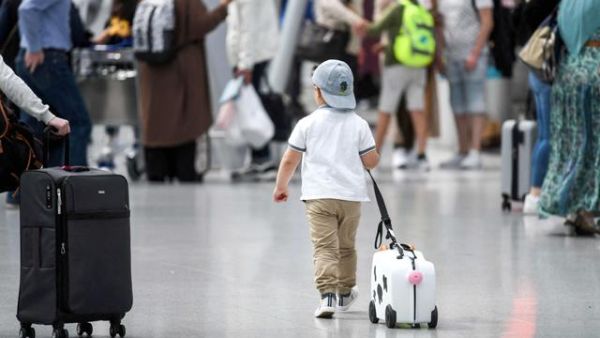 A little boy walks with his suitcase past travellers queing at the check-in counter on Friday at the airport of Duesseldorf as summer holidays begin in this western German area (AFP photo) A little boy walks with his suitcase