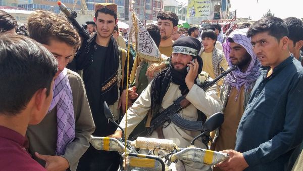 Taliban fighter (C) is seen surrounded by locals at Pul-e-Khumri on August 11, 2021 after Taliban captured Pul-e-Khumri, the capital of Baghlan province about 200 kms north of Kabul. (Photo by AFP) Biden suggested a political solution for afghanistan