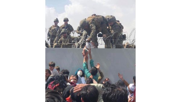 US Marine grabbing an infant over a fence of barbed wire during an evacuation at Hamid Karzai International Airport in Kabul on August 19, 2021. (Photo by Omar HAIDIRI / Courtesy of Omar Haidiri / AFP) U.S. pauses evacuation flights in Kabul as Qatar refuses to welcome more Afghans