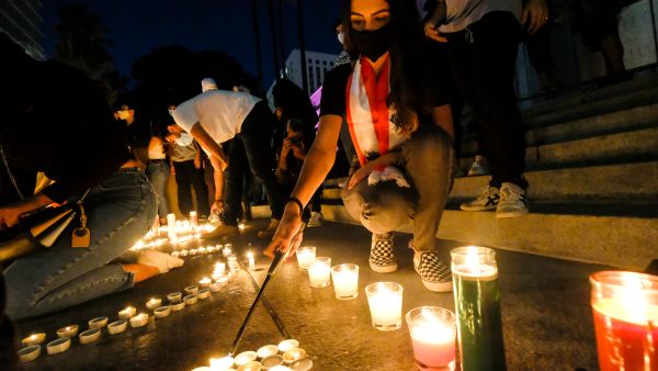 A woman lights candles during a candelight vigil for victims of Beirut's blast in front of the City Hall building illuminated with the colors of Lebanon in Los Angeles on August 6, 2020. “Despite the devastation wrought by the blast, Lebanese officials continue to choose the path of evasion and impunity over truth and justice,” Fakih said. “The UN Human Rights Council should immediately authorize an investigation, and other countries should impose targeted sanctions on those implicated in ongoing abuses and efforts to impede justice.”