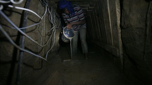 A Palestinian tunnel worker uses a bucket in underground tunnel