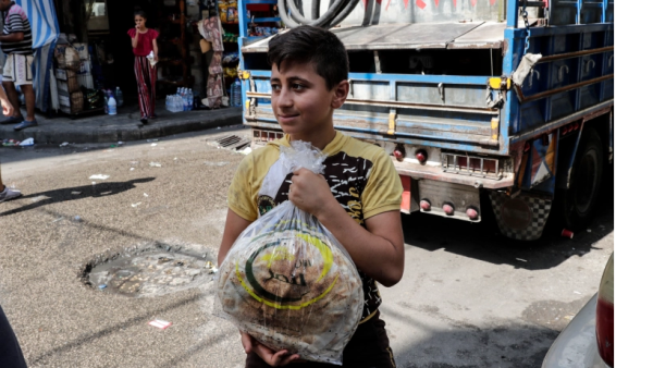 A young boy leaves a bakery with a bag of bread in a Beirut Suburb 