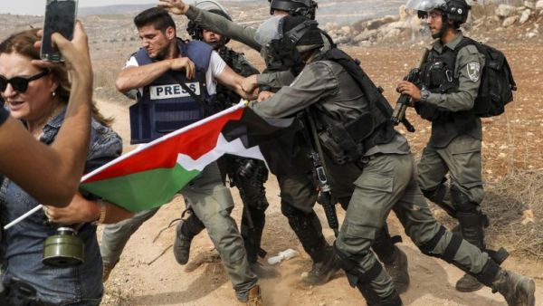 Israeli soldiers arrest a Palestinian journalist