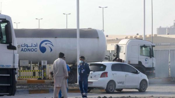 Men stand outside a storage facility of oil giant ADNOC 