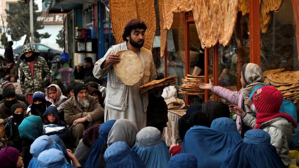 An Afghan man distributes bread to the people in need outside an eatery in Kabul on February 19, 2022. (Photo by Ahmad SAHEL ARMAN / AFP) Collapse of Afghanistan's Economy and Height of Humanitarian Crisis