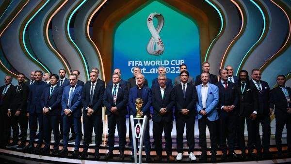 Coaches pose in front of the World Cup trophy during the draw for the 2022 World Cup in Qatar at the Doha Exhibition and Convention Center on April 1, 2022. (Photo by FRANCK FIFE / AFP)