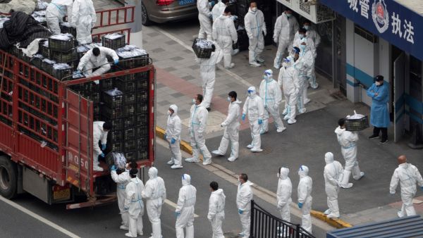 This photo taken on April 5, 2022 shows people wearing personal protective equipment (PPE) as they transfer daily food supplies and necessities for local residents during the Covid-19 lockdown in Shanghai. (Photo by AFP) covid-19 cases has hit a new record in China