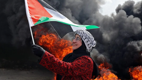 Palestinian woman holds up a national flag 