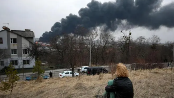 A youth sits on the top of a hill watching dark smoke and flames rising from a fire following an air strike in the western Ukrainian city of Lviv, on March 26, 2022. At least five people wounded in two strikes on Lviv, the regional governor said, in a rare attack on a city that has escaped serious fighting since Russian troops invaded last month. (Photo by Aleksey Filippov / AFP) Ukraine: Current Status and Future Scenarios