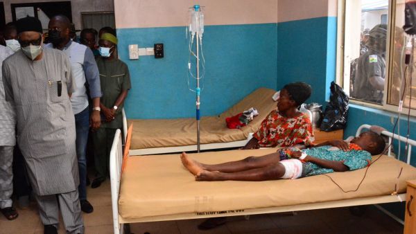 Graphic content / State officials walk past injured victims on hospital beds being treated for wounds following an attack by gunmen at St. Francis Catholic Church in Owo town, southwest Nigeria on June 5, 2022. (Photo by AFP) Nigerian church attack
