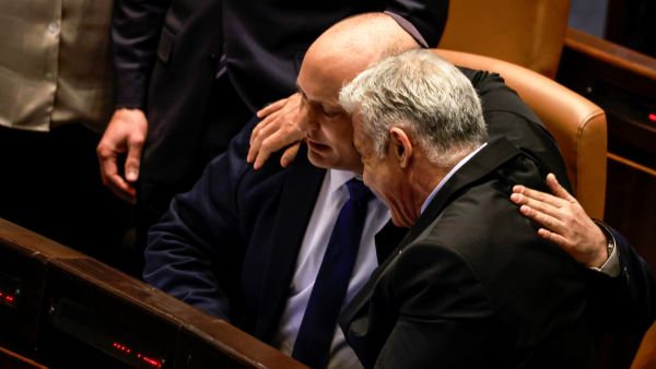 Israeli Minister of Foreign Affairs Yair Lapid (R) and outgoing Prime Minister Naftali Bennett, embrace each other at the Knesset (parliament), following the dissolution of the parliament, in Jerusalem on June 30, 2022. (Photo by Menahem KAHANA / AFP) War criminals