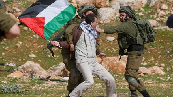 A Palestinian clutched by Israeli soldiers 