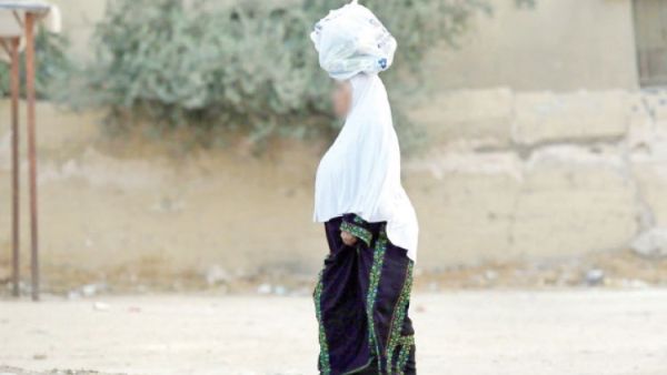 مسنة فلسطينية تحمل مشتريات فوق رأسها