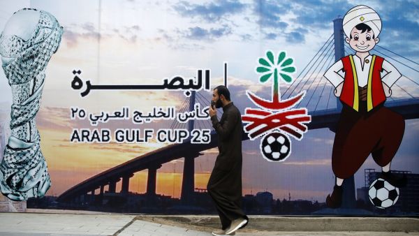 A man walks past a poster announcing the 25th Arabian Gulf Cup football championship, in the Al-Ashar district of Iraq's southern city of Basra, on January 5, 2023. (Photo by AHMAD AL-RUBAYE / AFP) Arabian Gulf Cup