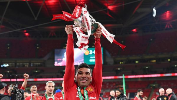 Manchester United's Brazilian midfielder Casemiro holds the trophy as Manchester United players celebrate their win on the pitch after the English League Cup final football match between Manchester United and Newcastle United at Wembley Stadium, north-west London on February 26, 2023. Manchester United clinched their first major trophy for six years with a ruthless 2-0 win against Newcastle in the League Cup final at Wembley on Sunday. (Photo by Glyn KIRK / AFP)