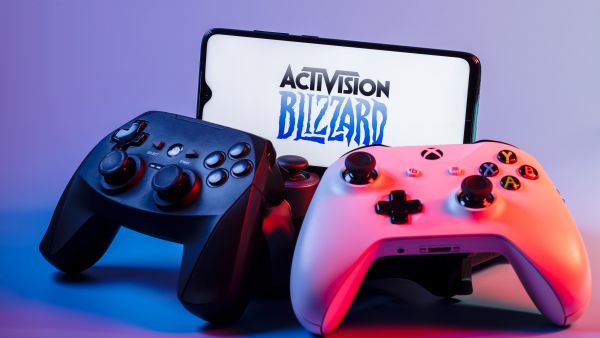 August 7, 2021: Activision Blizzard, Inc. is an American video game holding company. A smartphone with the Activision Blizzard logo on the screen on the pile of the gamepads.