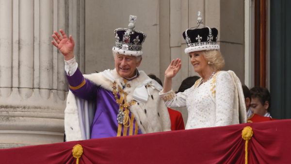 Britain's King Charles III wearing the Imperial state Crown, and Britain's Queen Camilla wearing a modified version of Queen Mary's Crown wave from the Buckingham Palace balcony after viewing the Royal Air Force fly-past in central London on May 6, 2023, after their coronations. (Photo by Daniel LEAL / AFP) King Charles III