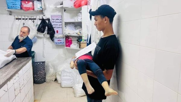 فتى فلسطيني من غزة ينتظر دوره لتكفين أخيه الشهيد- صورة من مواقع التواصل