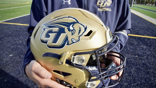 Chuck Goldstein, head football coach at Gallaudet University, holds a 5G-connected football helmet designed for deaf and hard of hearing players (Photo by Agnes BUN / AFP) American football