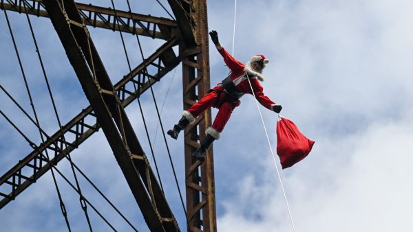 Guatemalan municipal firefighter Hector Chacon, dressed as Santa Claus, goes down a cable from a bridge to deliver presents to children (AFP) Santa Claus
