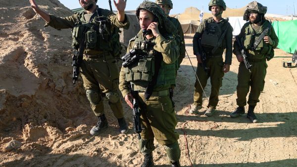  soldiers stand near the entrance of a tunnel 