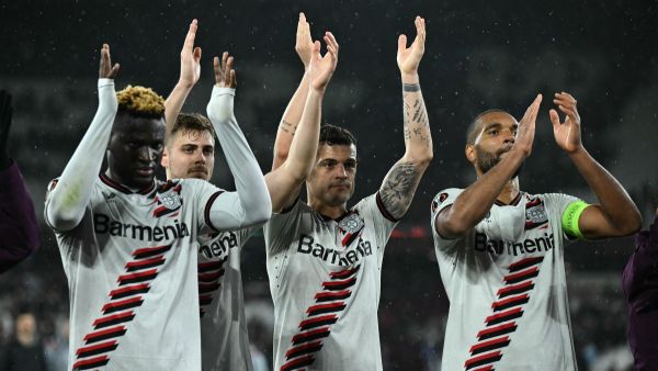 Bayer Leverkusen's Nigerian striker #22 Victor Boniface (L), Bayer Leverkusen's Swiss midfielder #34 Granit Xhaka (2R) and Bayer Leverkusen's German defender #04 Jonathan Tah (R) celebrate with their fans on the pitch after the UEFA Europa League quarter-final second leg football match between West Ham United and Bayer Leverkusen at The London Stadium in east London on April 18, 2024. The game finished 1-1, Leverkusen winning 3-1 on aggregate. (Photo by Ben Stansall / AFP)