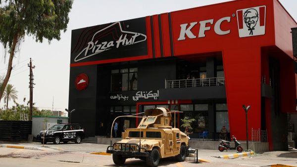 Iraqi security forces vehicles are stationed in front of a Kentucky Fried Chicken (KFC) and Pizza Hut fast food restaurants in the Al-Jadriya neighbourhood in Baghdad on May 30, 2024. (Photo by AHMAD AL-RUBAYE / AFP)