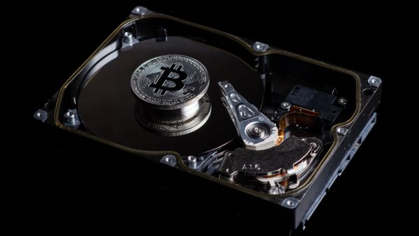 Silver Bitcoin coin on the opened HDD disk