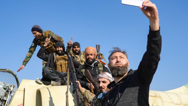 Anti-government fighters pose for a "selfie" picture on a Syrian regime military aircraft at the Kweyris military airfield in the eastern part of Aleppo province on December 3, 2024. (Photo by Rami al SAYED / AFP) Anti-government fighters