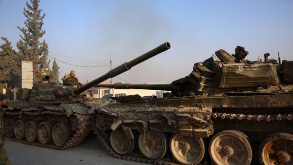Anti-government fighters sit in tanks left behind by Syrian regime forces in Hama