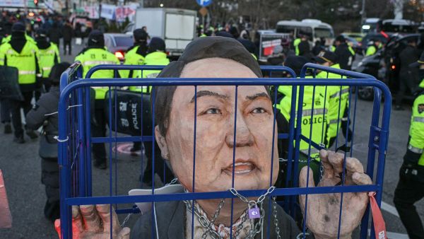 An effigy of South Korean President Yoon Suk Yeol is seen next to police during a protest following the result of the second martial law impeachment vote outside the National Assembly in Seoul on December 14, 2024. South Korean lawmakers on December 14 voted to remove President Yoon Suk Yeol from office for his failed attempt to impose martial law last week. (Photo by ANTHONY WALLACE / AFP) South Korean parliament votes to impeach president Yoon Suk-yeol