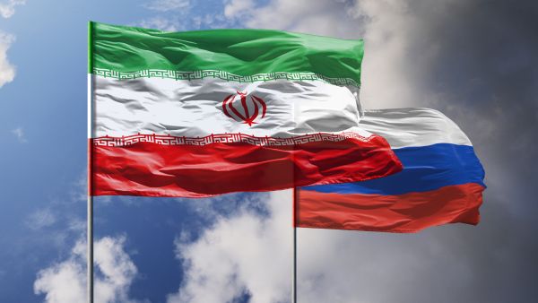 صورة تُظهر أعلام إيران وروسيا مرفوعة على خلفية سماء زرقاء