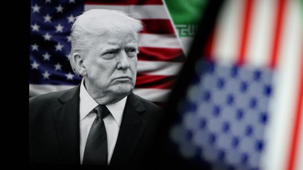 يظهر الرئيس الأمريكي دونالد ترامب خلف علم الولايات المتحدة الأمريكية.