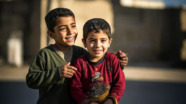طفلان فلسطينيان يبتسمان داخل مخيم للنازحين في خان يونس جنوب قطاع غزة خلال تجمع لمتابعة مباراة في كأس العالم 2026.