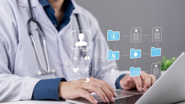 طبيب يستخدم حاسوباً محمولاً مع ظهور رموز رقمية تمثل السجلات الطبية 