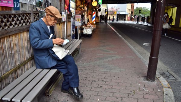 Elderly Japanese Man sitting alone in the street