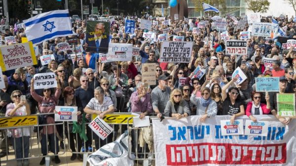Israeli protesters raise signs as they demonstrate against Prime Minister Benjamin Netanyahu in the wake of police recommendations to indict corruption, in the coastal city of Tel Aviv on Feb. 16, 2018. 
(JACK GUEZ / AFP)