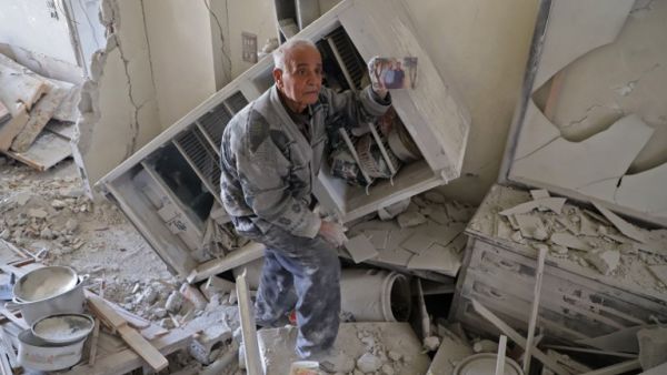 An elderly Syrian man shows a family picture after he recovered it from the rubble of his house in Kafar Batna in the Syrian rebel enclave of Eastern Ghouta on Mar. 1, 2018 following reported air strikes by Syrian government forces. 
Syrian and Russian forces kept up military pressure on rebel-held Eastern Ghouta today as their controversial unilateral truce failed to yield a humanitarian breakthrough.
(AMER ALMOHIBANY / AFP)